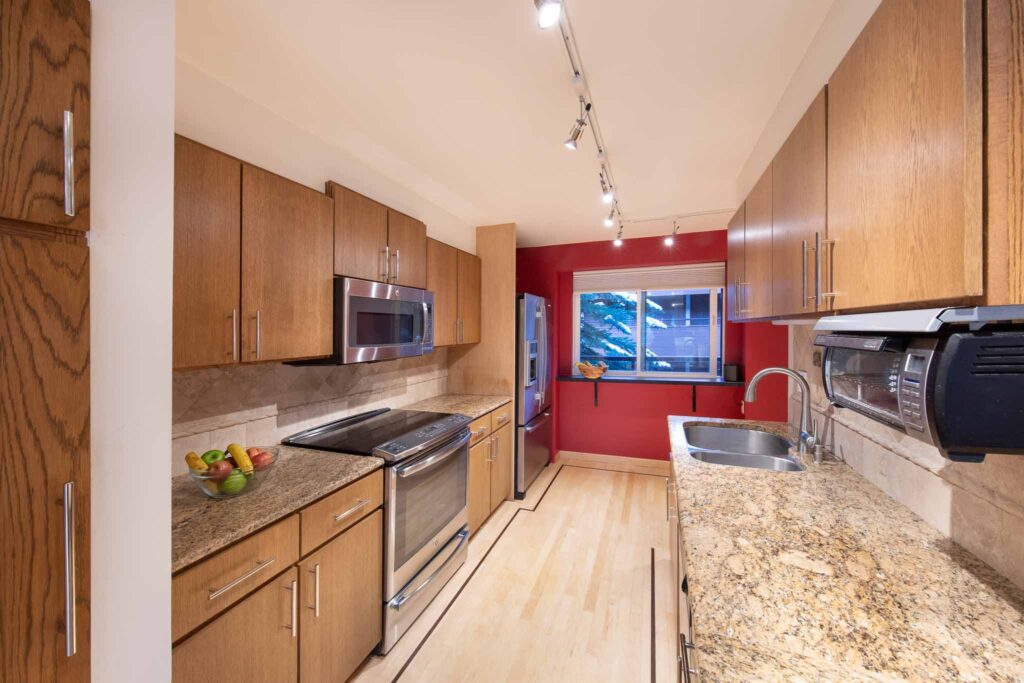 Interior kitchen of Vine development with accent wall, tan marble counters, and oak cabinets