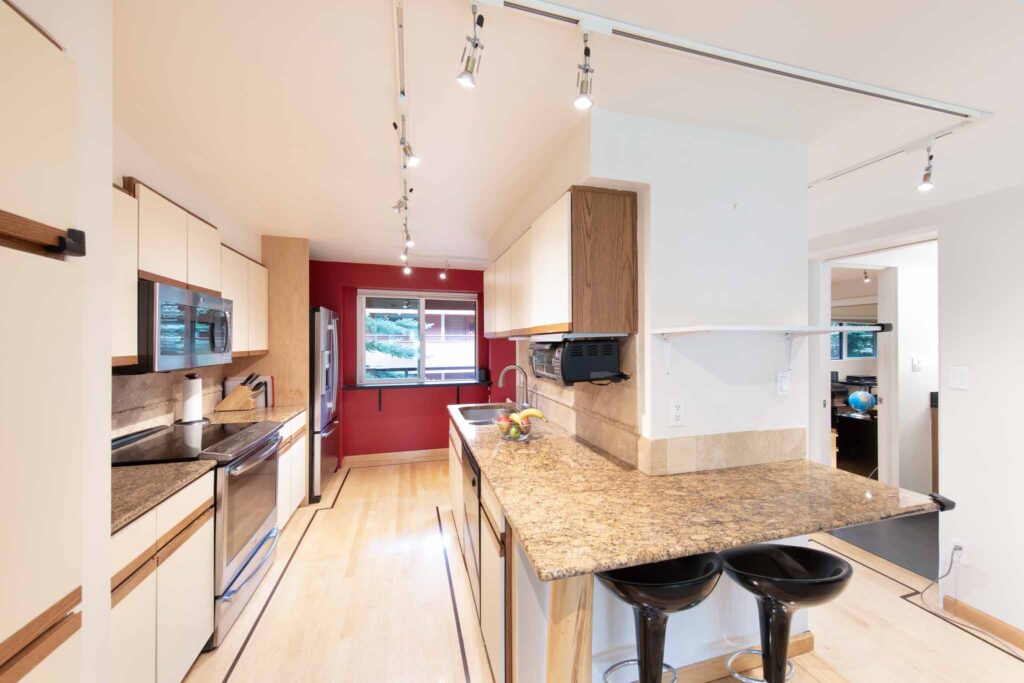 Interior kitchen view at Vine development containing red accent wall and tan marble counters