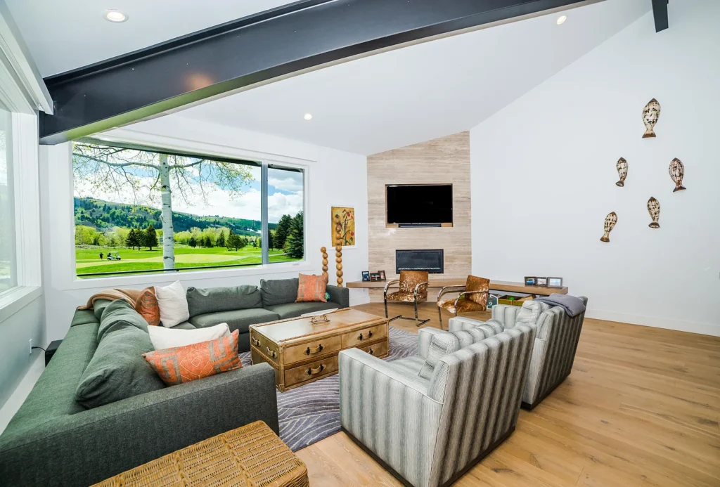 Interior living area with green couch, a leather chest in center and big window showing the country side at Golf Lane