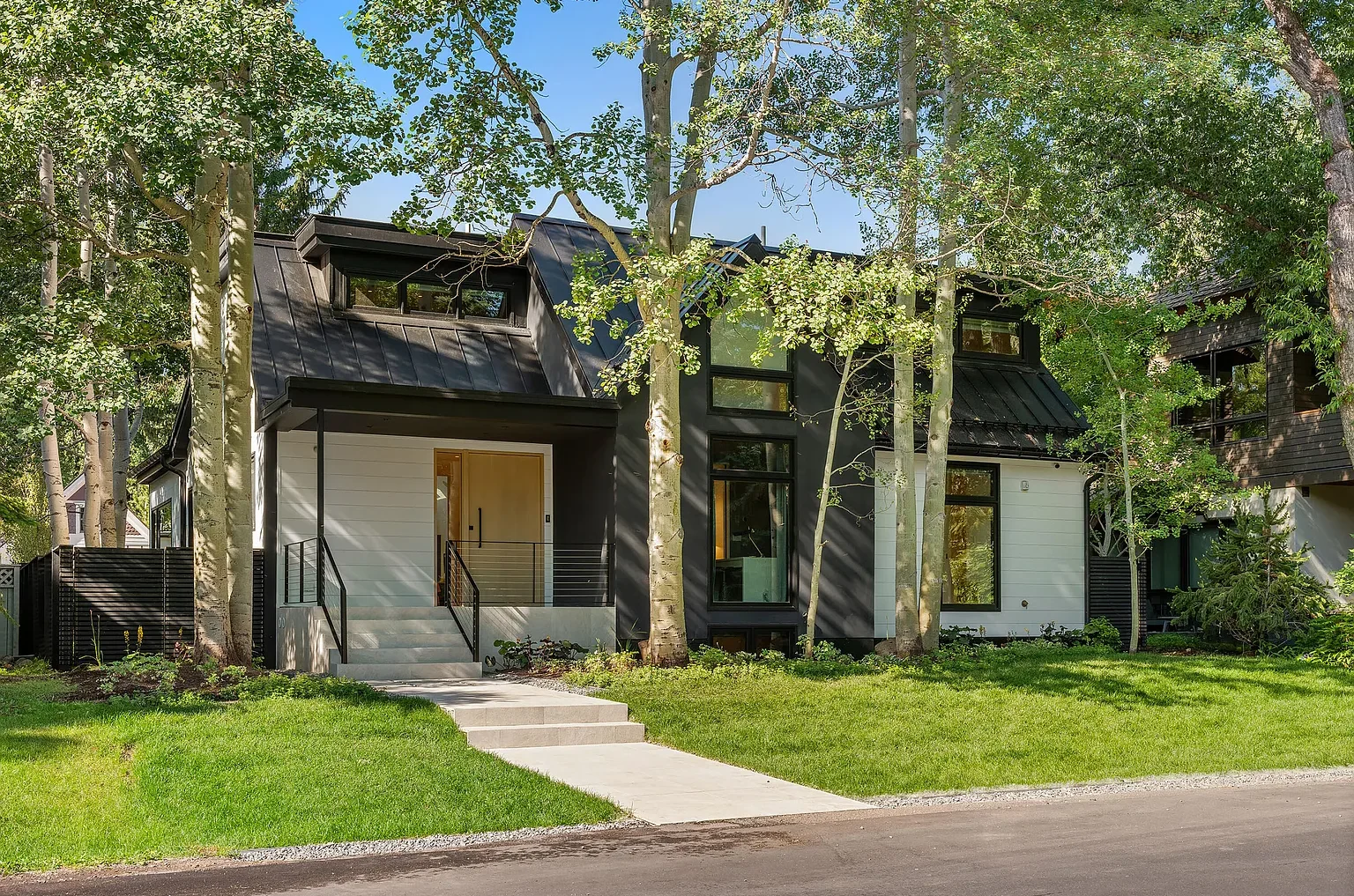 Front exterior view of home at Smuggler set behind trees with black and white siding