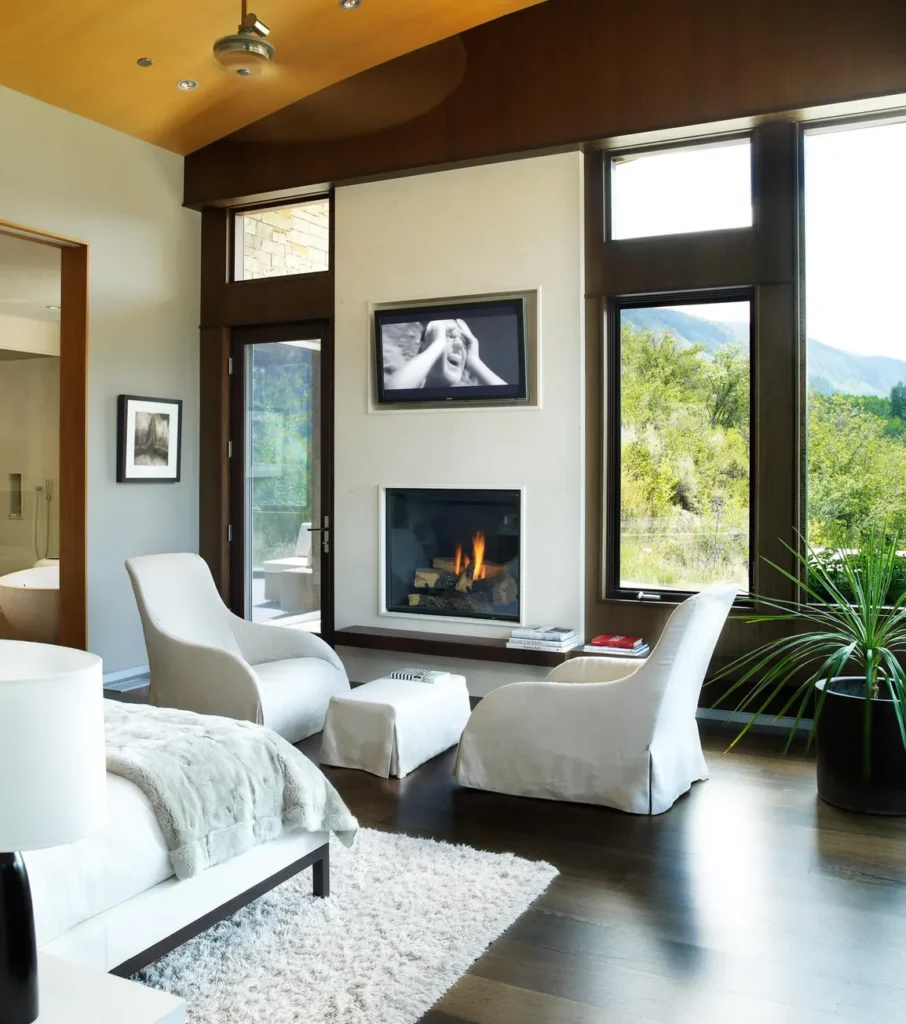 Interior master bedroom with dark wood floor and white bed spread and chairs at Smuggler Mountain Residence