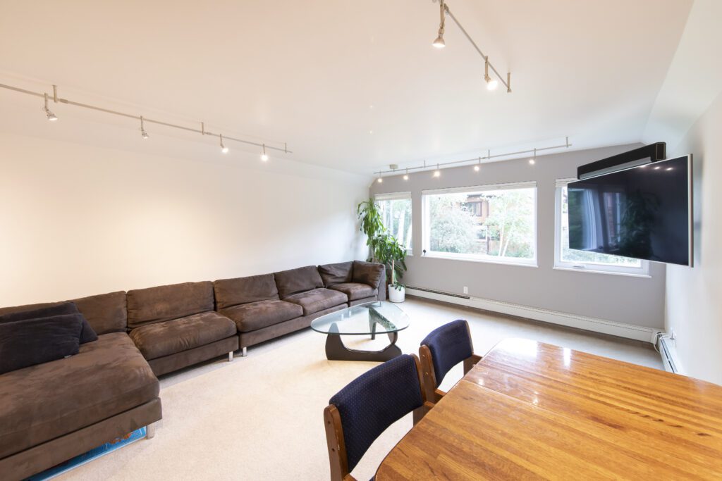 Interior living area with brown suede couch and large screen tv at Vine development