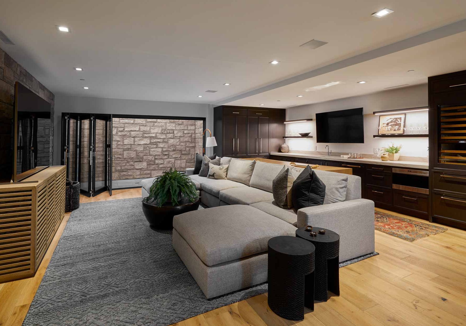 Living room area with long sectional couch, fern, and large screen tv at the Hallam residence