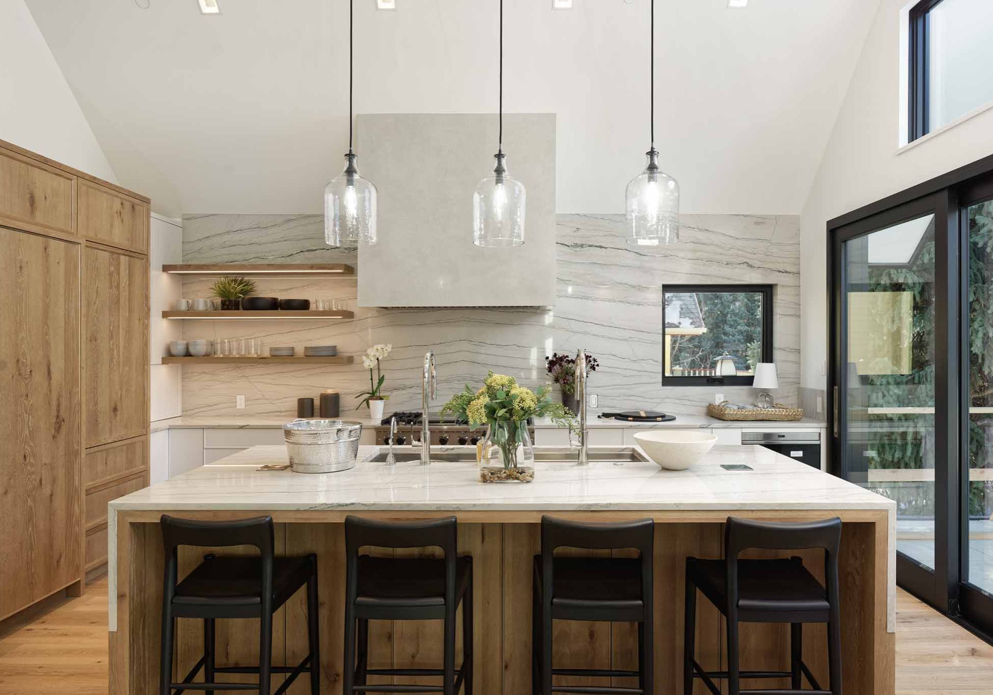 Interior view of Hallam development kitchen island with chairs near large sliding doors and hanging lights