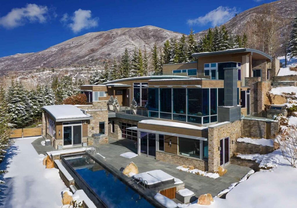 Wide exterior view of development containing pool, large bay windows, and stone siding